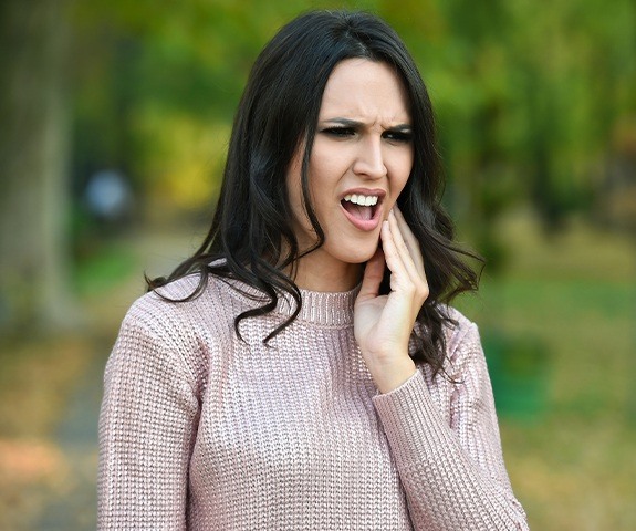 Woman in need of emergency dentistry holding cheek