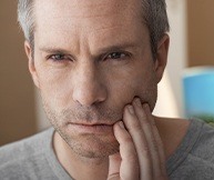 Man with lost dental filling holding cheek