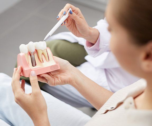 Dentist and patient looking at dental implant model