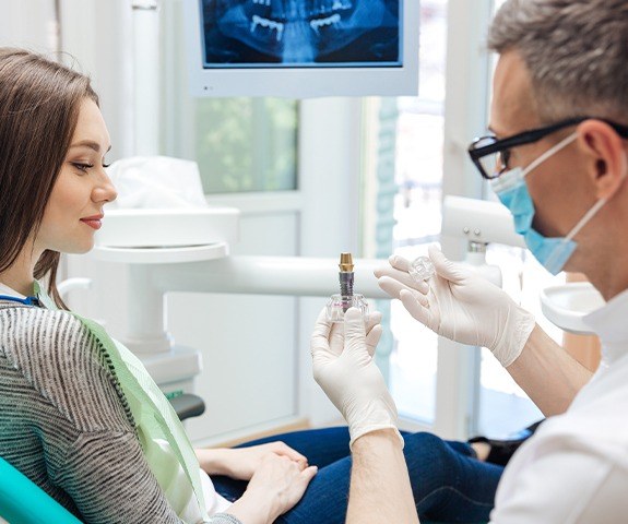 Dentist showing patient dental implant model