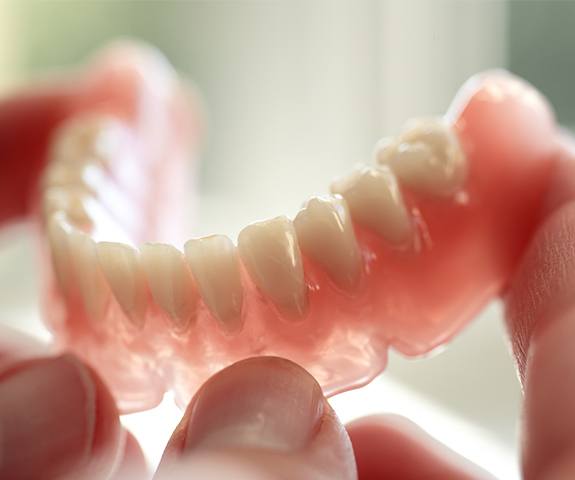 Hand holding a full denture