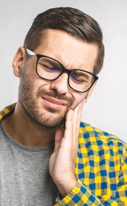 Man in need of emergency dentistry holding cheek